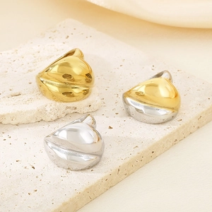 Sculptural chunky stainless steel rings in gold and silver finish on a stone plate
