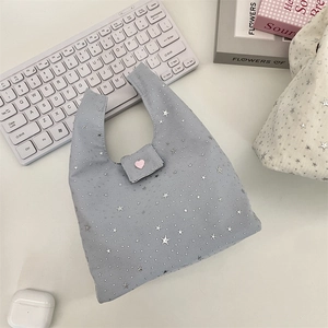 Detailopname van de sterrenprint shopper met roze hartbedeltje en metalen kliksluiting