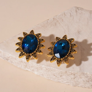 Vintage-Ohrstecker mit blauem Kristall und goldenem Sonnenblumen-Design auf Stein