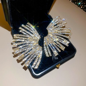 Detailed view of fan-shaped gold earrings with pavé crystals on black velvet display