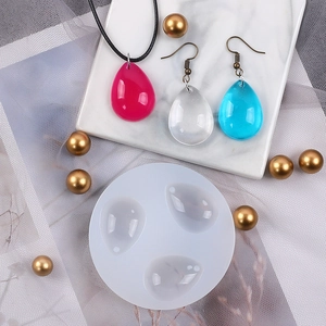 Detailed view of round silicone mold and finished water-drop resin pendants for DIY jewelry