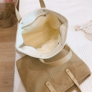 Detail view of woven handbag showing beige fabric lining and internal zipper pocket