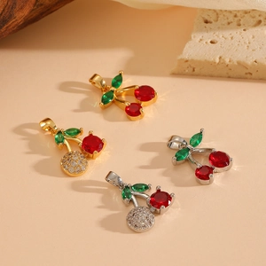 Detailed view of cherry pendants with red and green zircons on a textured stone base