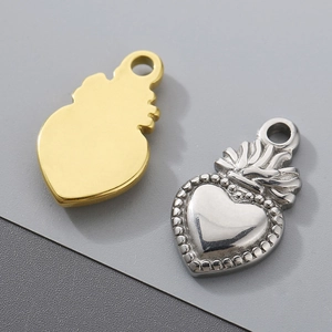 Detailed view of gold and silver stainless steel heart pendants with flame crown designs