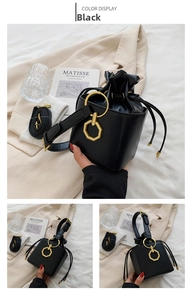 Detail view of a black drawstring bucket bag featuring unique golden geometric hardware buckles