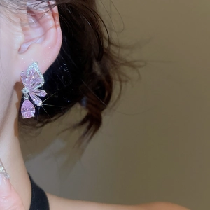 Macro shot of silver butterfly earrings with pink pear-cut crystals on model