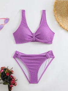 Detailed view of purple textured bikini fabric with beach hat and summer accessories