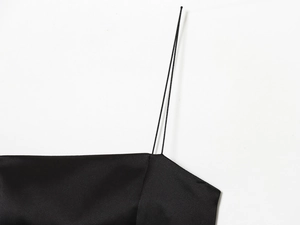 Détail de la fine bretelle sur une robe en satin noir élégante avec des coutures soignées
