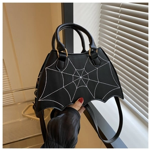 Detail of black bat-shaped PU handbag with white spider web embroidery in gothic style