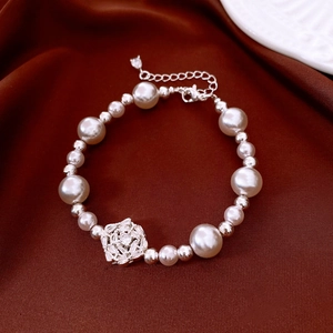 Macro detail of French style pearl bracelet with zircon flower pendant on brown silk fabric