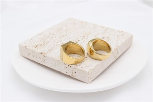 Polished gold-plated titanium rings displayed on textured stone blocks for men