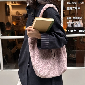Detail view of pink leopard print plush tote bag on a model in a stylish winter street setting