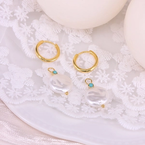 Detailed macro view of 18k gold plated hoops and cream pearl pendants on white lace