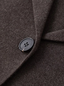 Gros plan sur la maille marron foncé avec bouton noir sur le revers du gilet