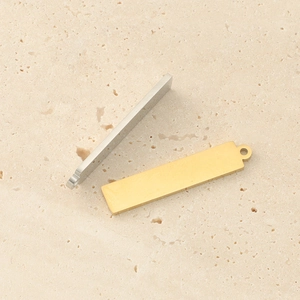 Detailed view of gold and silver rectangle stainless steel pendants on stone background