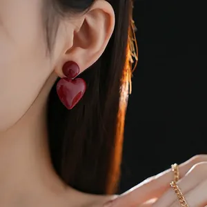 Elegant deep red heart drop earrings worn by a model in a minimalist style