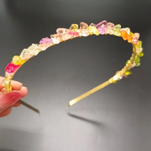Macro detail of handmade gold crown headband featuring vibrant multicolor crystal stones