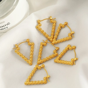 Minimalist gold triangle bead earrings with metallic texture on white silk background