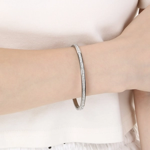 Dettaglio ravvicinato di un bracciale rigido in argento con cristalli lucidi
