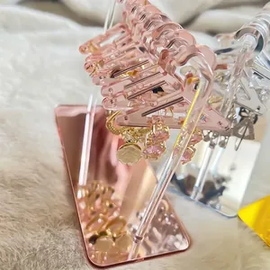 Pink acrylic clothes hanger earring organizer with mini hangers on fuzzy carpet background