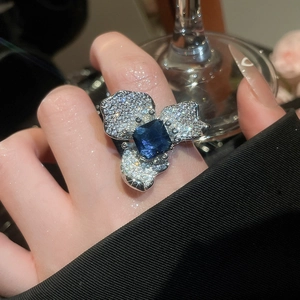 Gros plan d'une bague fleur luxueuse en zircone avec pierre bleue au doigt