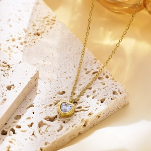 Close-up of gold plated heart pendant necklace with light blue zircon on stone base