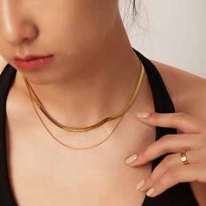 Detailed view of layered gold snake bone chain necklace and minimalist hollow ring set