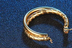 Macro shot of double layered gold titanium steel hoop earrings with hammered texture finish