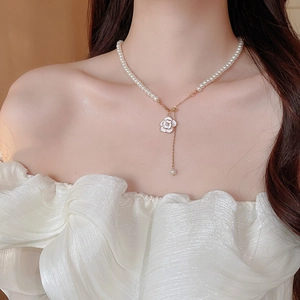Close-up of elegant camellia flower pendant on pearl necklace with tassel detail