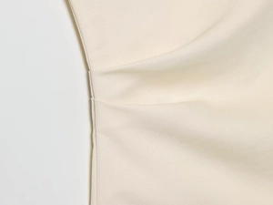 Makro-Detail des cremeweißen Satinstoffs mit eleganten Falten und glatter Textur