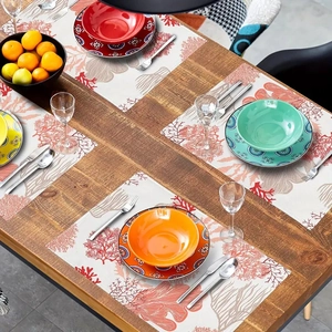 Top view of rectangular blue coral placemats with colorful ceramic dinnerware on a wooden table