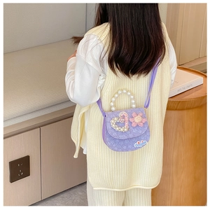 Detail of purple girl's bag with pearl handle, plush flower, and heart decoration