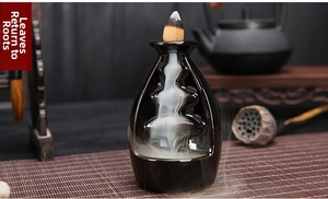 Macro view of black ceramic backflow incense burner with smoke flowing through layered steps