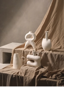 Detailed macro view of four matte white ceramic vases with minimalist organic shapes