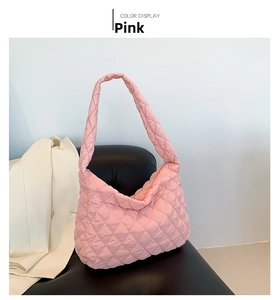Detail of pink quilted puffer tote bag with large diamond stitching on a leather sofa