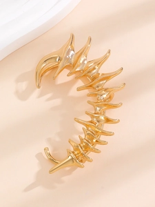 Macro shot of gold punk fishbone ear cuff with creative geometric dragon shape and glossy finish