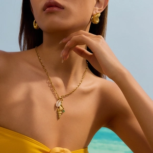 Détail d'un ensemble collier et boucles d'oreilles coquillage doré avec gemme verte
