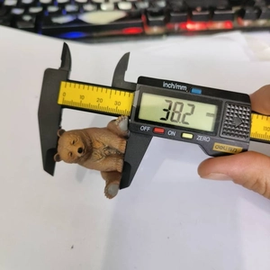 Detailed measurement of a brown bear figurine showing a height of 38.2 mm with a caliper