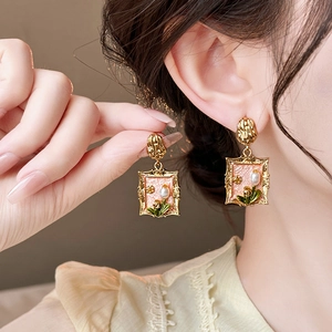 Detail of vintage gold flower earrings with pink enamel and pearl worn by a model