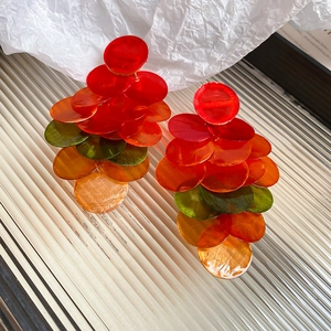 Macro detail of layered translucent shell earrings with colorful gradient disk fringe