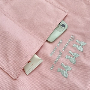 Vue détaillée de la broderie nœud menthe et poche sur un sac cabas en toile rose
