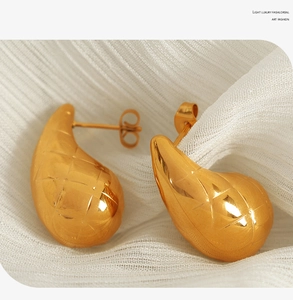 Macro shot of gold-plated chunky teardrop earrings with elegant diamond lattice texture