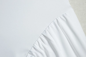Macro view of detailed pleats and fine fabric texture on white sleeveless dress