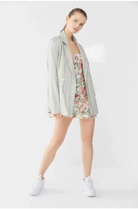 Detail of a casual plaid blazer styled with a floral mini skirt and white sneakers
