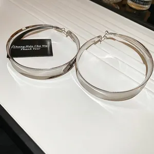 Close-up of polished silver hoop earrings displayed on a white textured jewelry tray