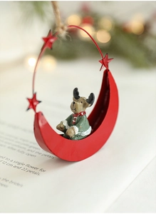 Close-up of red metal moon Christmas ornament with a cute reindeer and warm bokeh background