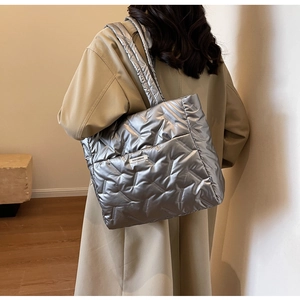 Détail du sac cabas matelassé argenté avec coutures en V et étiquette logo mode