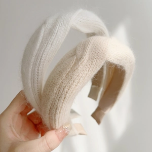 Detailed macro view of soft beige and cream knitted plush fabric on cross-knot headbands