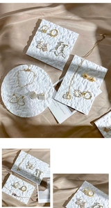 Detail view of gold and pearl jewelry set displayed on a white textured stone tray