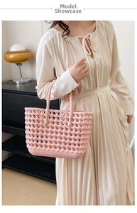 Detail of pink woven hollow basket bag held by model wearing a beige pleated dress